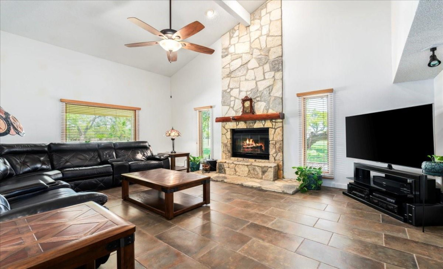  The spacious living room captivates with a soaring vaulted ceiling and a floor-to-ceiling stone fireplace featuring a mesquite log mantel and stainless steel flue—perfect for cozy evenings with loved ones. 