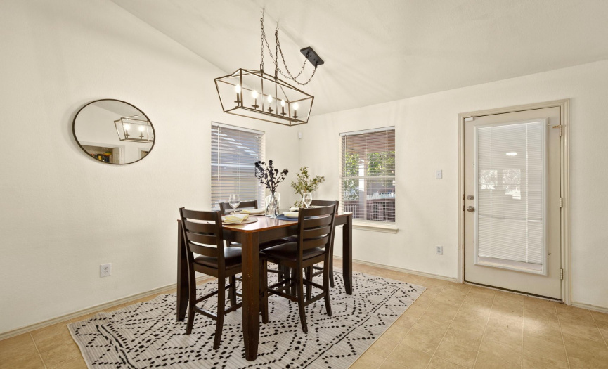 Adjacent to the kitchen is the bright and airy breakfast area, illuminated by a modern chandelier.