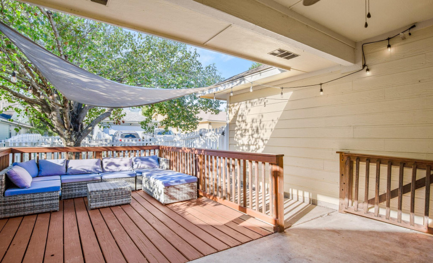 Step into the private fenced-in backyard, a shaded oasis with a covered patio and a wood deck for outdoor relaxation.
