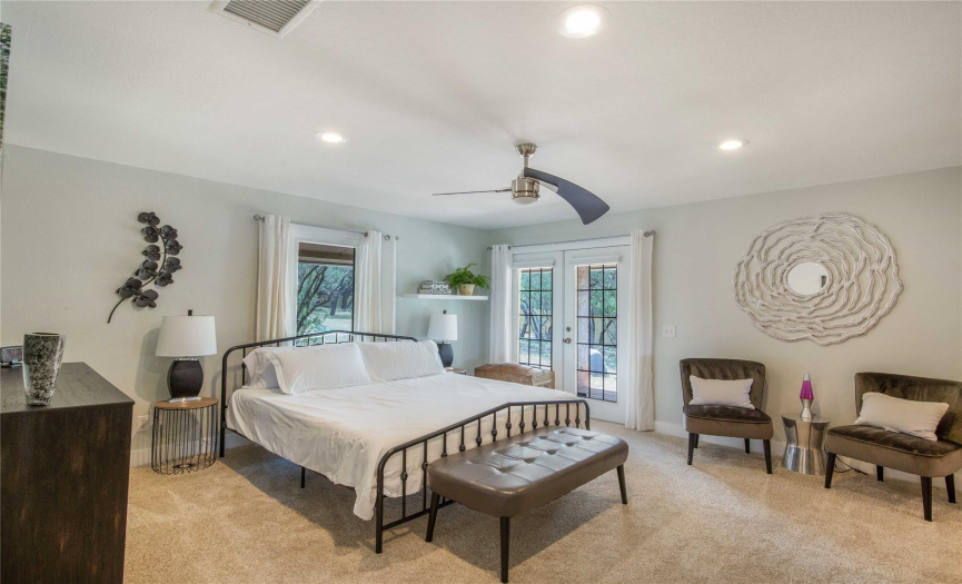 Experience tranquility in the primary bedroom, illuminated by recessed lighting and cooled by a modern ceiling fan, offering the perfect retreat for relaxation.