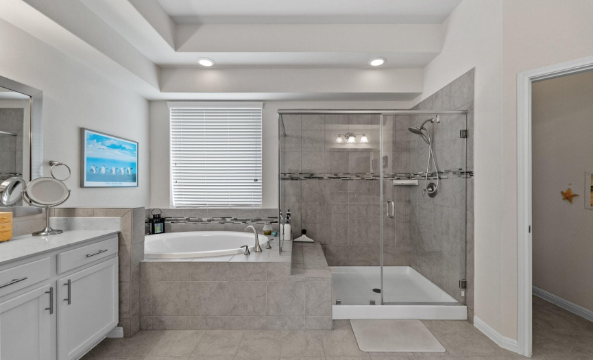 This exceptional primary bathroom boasts an exquisite design and thoughtful layout, featuring separate double vanities and a luxurious combination of a shower and a garden tub. 