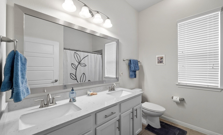 This spacious bathroom features double sinks and is conveniently situated between the secondary bedrooms.