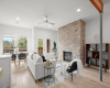 Featuring tall ceilings, LED recessed lighting, and a striking wood-burning fireplace nestled in a brick wall hearth. 
