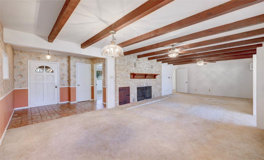 The large living area is accented by wooden beams and a stacked stone WB fireplace.