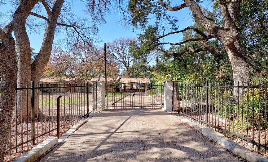 An attractive iron fence and gate surround the  front yard. 