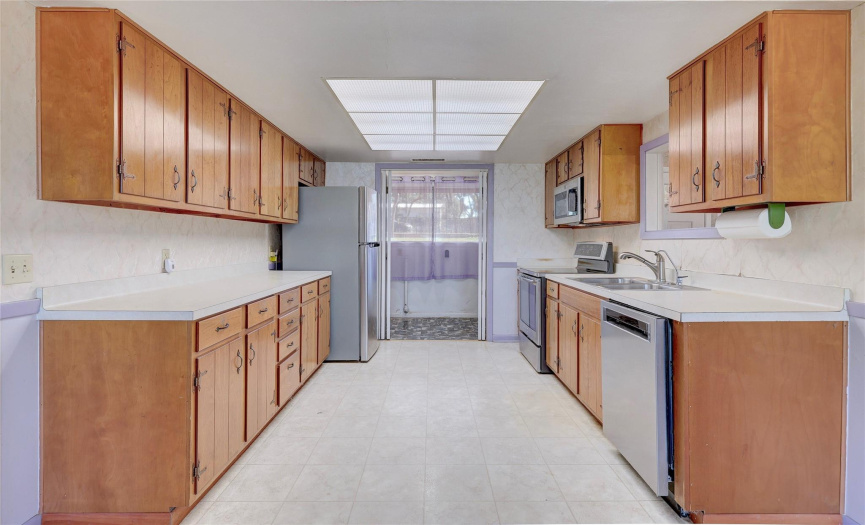 A galley kitchen continues into a light filled laundry room.