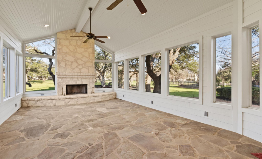 Escape to this expansive covered patio, where a majestic fireplace creates a focal point for evening relaxation. Encased in natural stone and with a panoramic view of the lush grounds, this space blends indoor comfort with the beauty of outdoor living.
