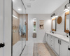 Recently remodeled primary bathroom with polished porcelain tile flooring, quartz countertops, walk in shower and custom closet