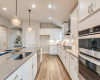 Featuring sleek quartz countertops, decorative tile backsplash, pendant lighting, and SS appliances including a built-in wall oven & microwave, gas cooktop with a designer vent hood, and a dishwasher. 