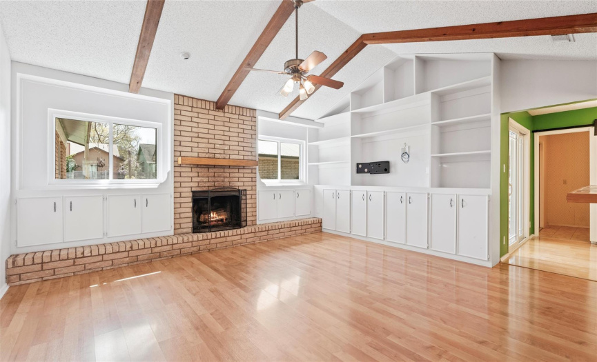The great room serves as the heart of the home with gorgeous vaulted ceilings and exposed wood beams, plus a cozy fireplace nestled in an expansive brick hearth. 
