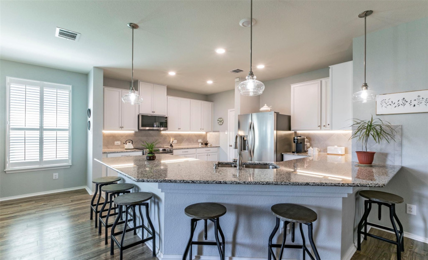 The bright airy kitchen has nice white cabinets, granite counters, and a beautiful backsplash. 