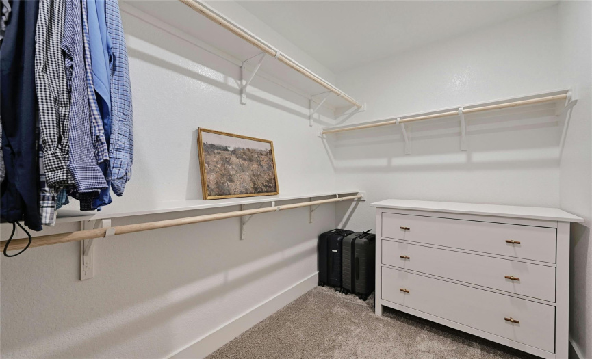 The primary closet is large with railings and shelves for storage.