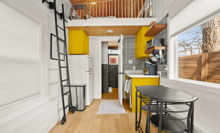 Tiny home kitchen/dining area with loft that has a king size bed