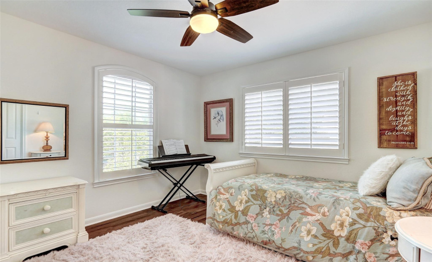 boasting the warmth of wood floors and the classic charm of plantation shutters. Natural light dances from both windows, creating an inviting atmosphere that exudes comfort and sophistication. 