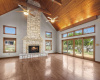 MASSIVE STONE FIREPLACE WITH DOUBLE CEILING FANS ON THE SOARING WOOD CEILINGS.