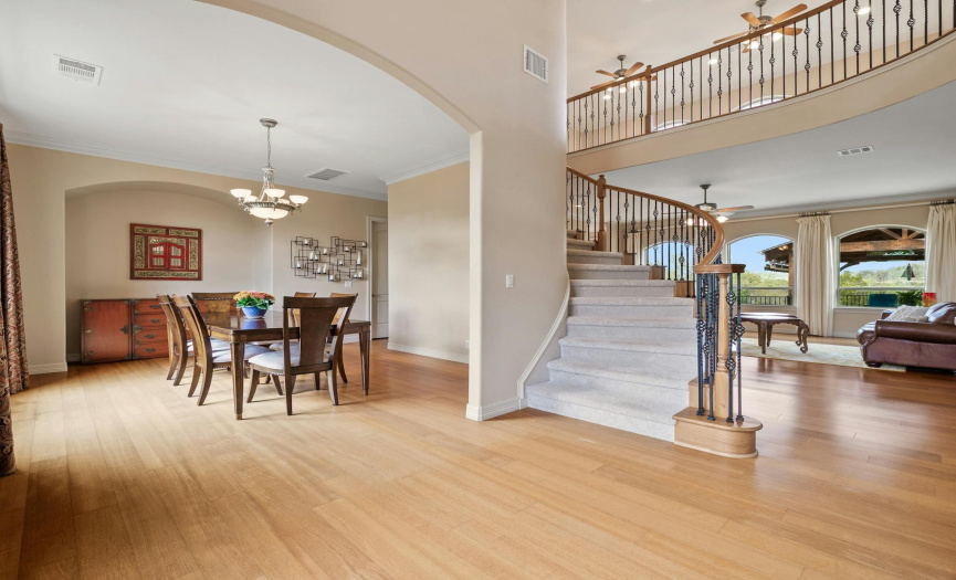 As you step inside the grand foyer, you're greeted by soaring two-story high ceilings flanked by formal living and dining rooms, adorned with pristine wood flooring and neutral-toned walls painted in 2019, creating an ambiance of timeless elegance