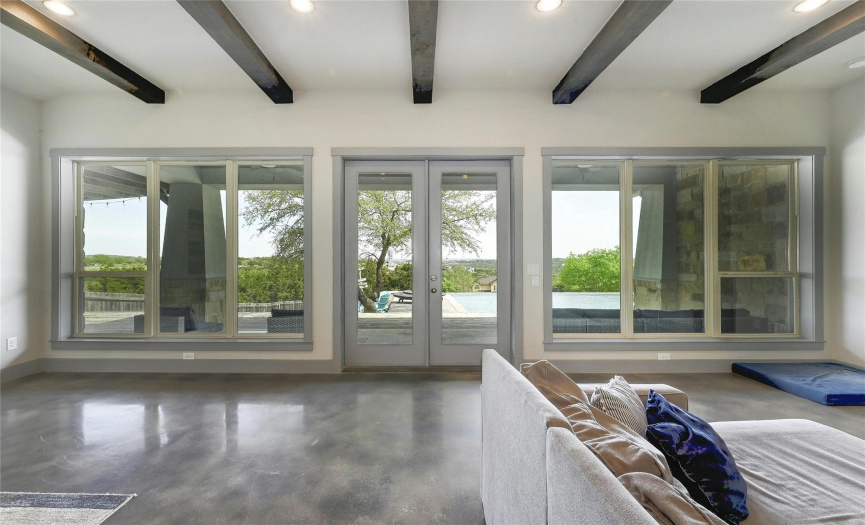 A wall of windows and doors frames in the outdoor living, pool, and skyline.