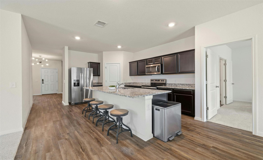 Discover culinary inspiration in the well-equipped kitchen, featuring a large center island and breakfast bar for meal preparation and casual dining.