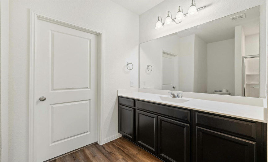 Experience convenience and elegance in the primary bathroom, featuring ample counter space atop sleek countertops.