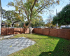 Fenced front yard with patio and large shade tree