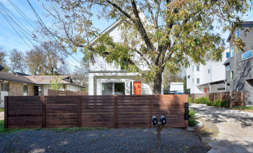 Fenced front yard with patio and large shade tree
