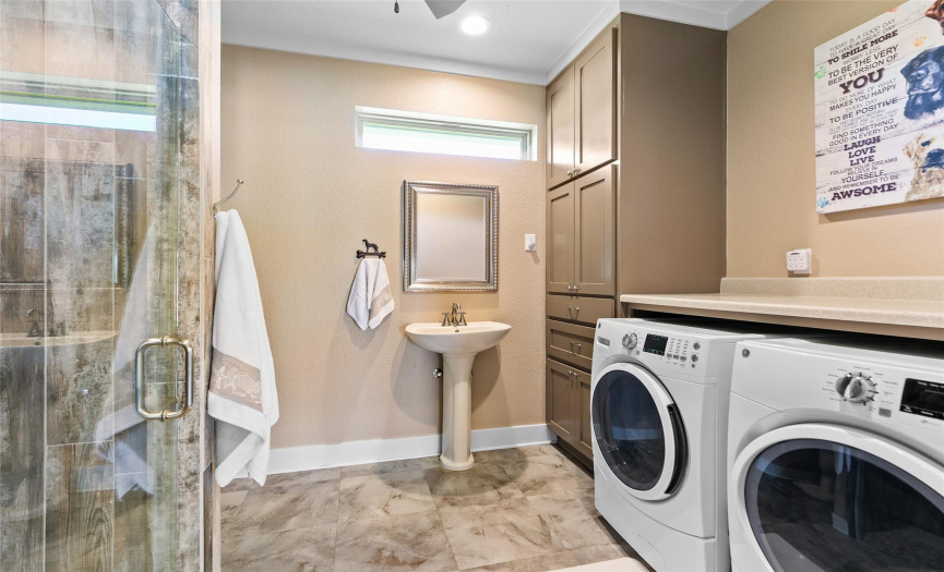 Guest house bath has a full size washer and dryer, floor to ceiling storage and a walk-in shower. 