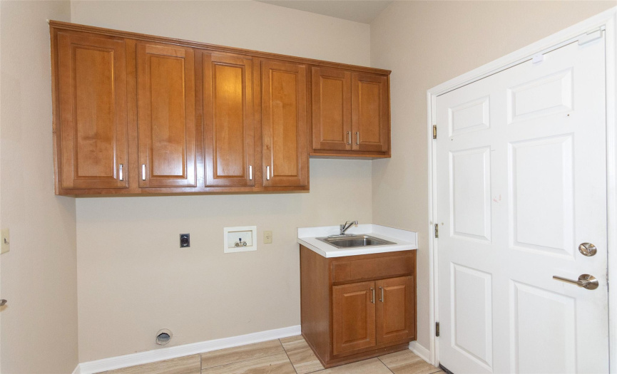 Across from the secondary bathroom is the utility room.  Plenty of room for both front loading machines next to the sink.  Plenty of cabinets, and the room is also big enough for two refrigerators and a freezer, along with a sewing machine, and your brooms and mops!