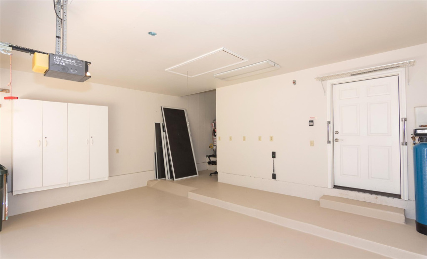 The garage has a fresh coat of paint on the floor.  You see all the screens for  the home, and there is even a stop-in-go red light/green light on the wall to keep from hitting the wall opposite the utility room.  Even more storage in the cabinets attached to the walls.