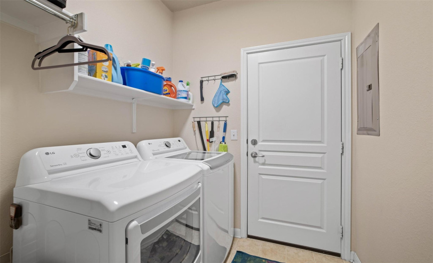 The laundry room is accessible to the garage and offers two shelves and a hanging rod.