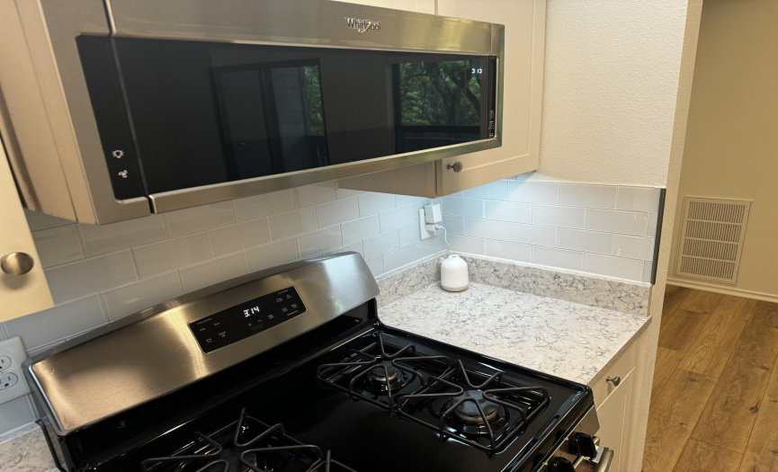 New low-profile microwave with vent hood.  Complimenting quartz counters and backsplash