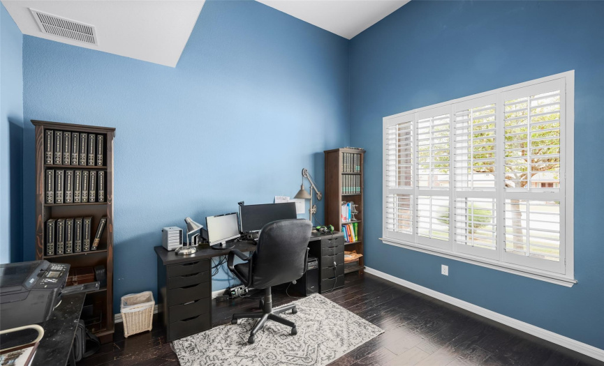 Double doors at the front of the dining room open into this nice and secluded home office with tall ceilings and windows overlooking the front yard with custom plantation shutters. 