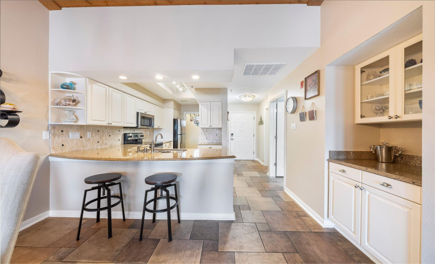 The kitchen showcases stainless steel appliances, granite countertops, and a tasteful tile backsplash, while the adjacent laundry room offers convenience with washer/dryer connections.