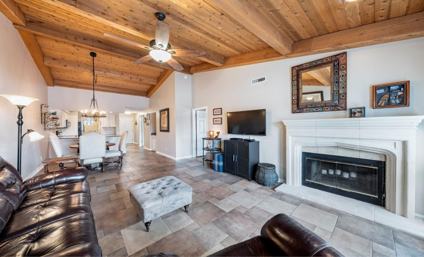 Step into the living area adorned with distinctive cedar and beamed vaulted ceilings, complemented by elegant tile flooring and a bespoke wood-burning fireplace with a custom surround.