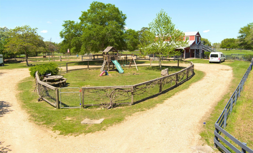 Circular drive to barn area with fenced play area and playscape