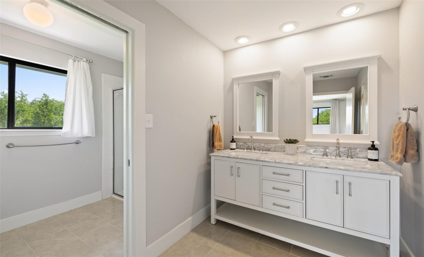 The primary bathroom has dual vanities.  The walk-in shower and commode are in a separate area.