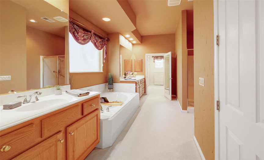The primary bathroom is complete with dual vanities, a jetted tub, and a separate walk-in shower for ultimate relaxation.
