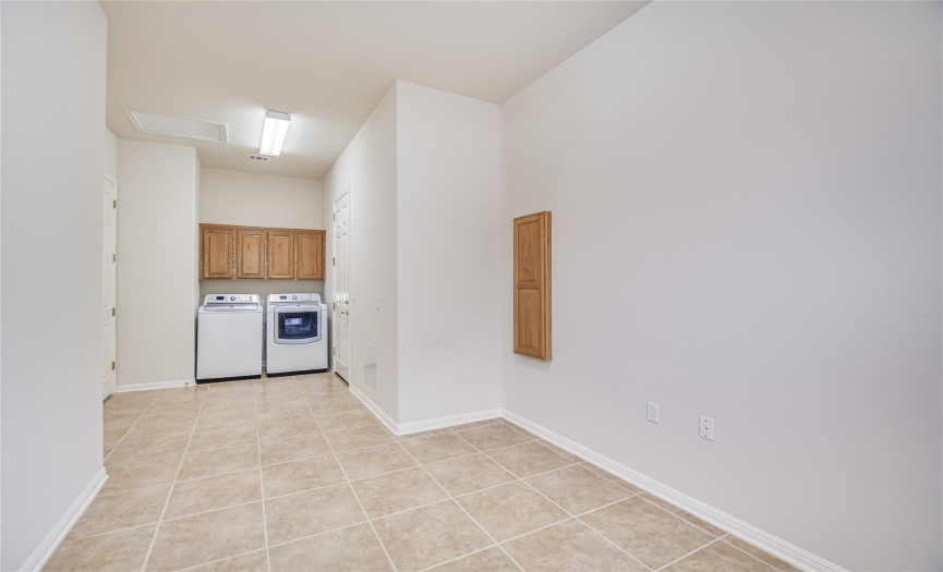 Laundry room with wood cabinets and washer/dryer, ironing board wall cabinet.