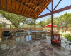 Large covered and extended patio with custom ceiling, outdoor kitchen and flagstone flooring.