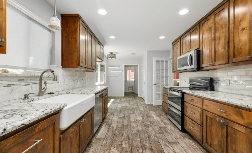 This galley-style kitchen combines functional design with high-end finishes to create a space that is both stylish and practical. It features custom cabinets along both walls, offering ample storage for all your kitchen needs. The countertops are crafted from luxurious granite, providing plenty of durable and attractive workspace.