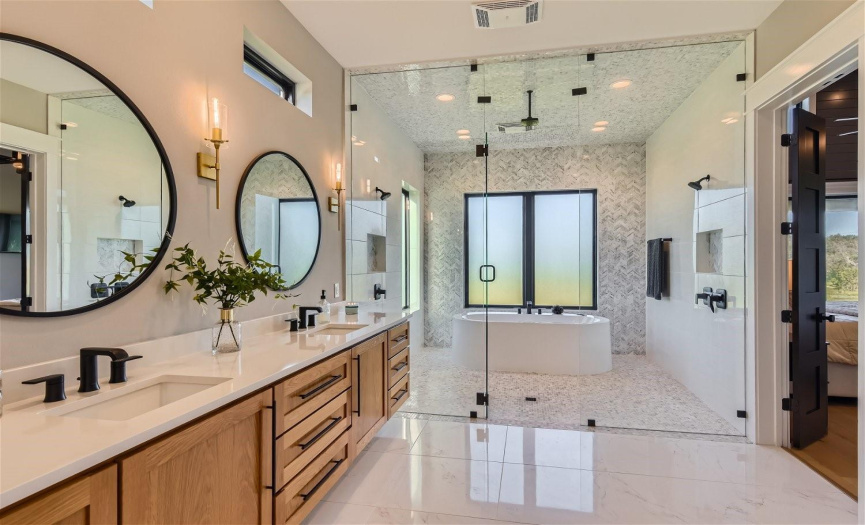 Relax in the spa-like ambiance of the primary bathroom, featuring a generously-sized walk-in shower with an integrated tub, paired with dual sinks nestled within modern 'floating' cabinets, providing abundant storage space.