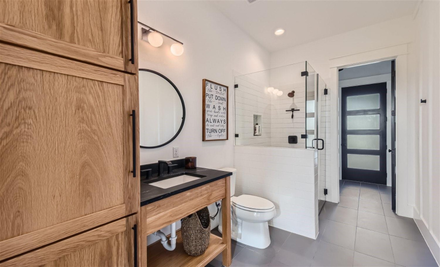 The guest bathroom offers convenient access to the back patio and pool area, featuring soapstone countertops, ample storage, and a designated spot for belongings, ensuring a seamless transition from outdoor fun to indoor comfort.