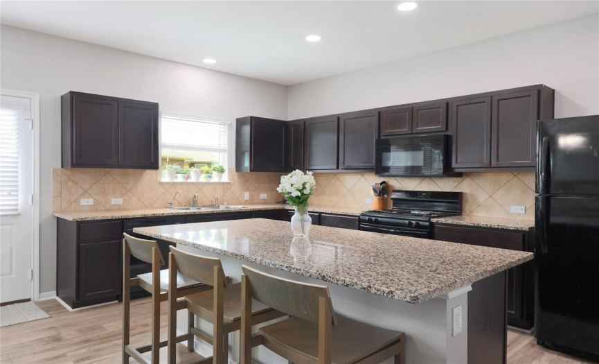 The large kitchen features lots of cabinets, ample counter space, and durable granite countertops. 