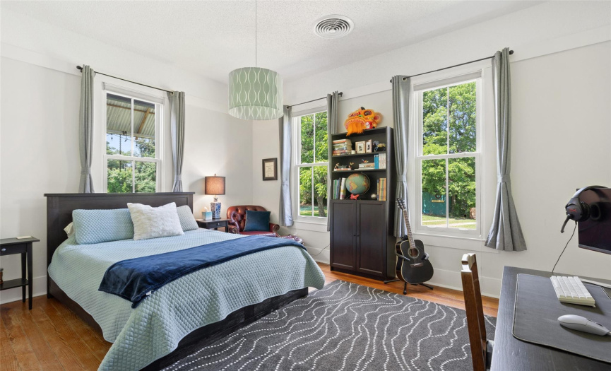 A bright bedroom with high ceilings and numerous windows.