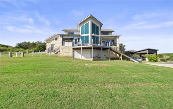 Nestled atop a gentle hill, this picturesque home offers breathtaking views of the tranquil Lake LBJ. Its design is a harmonious blend of modern architecture set among its natural surroundings. Tall, elegant windows wrap around the corner point, inviting abundant natural light to flood the interior while framing the serene vista beyond.