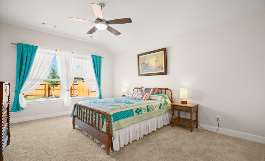 Experience relaxation in the spacious primary bedroom, featuring plush carpet flooring and motorized blinds for personalized comfort.