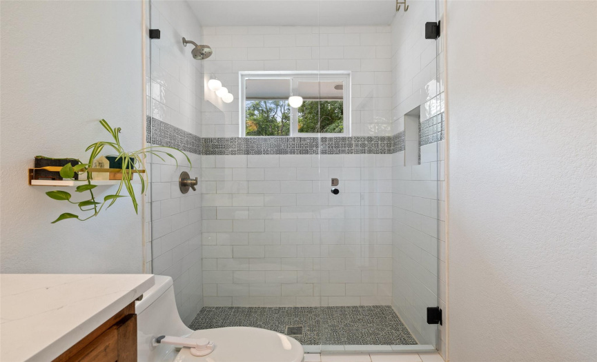 Oversized walk-in shower has tile detail, niche and frameless glass.