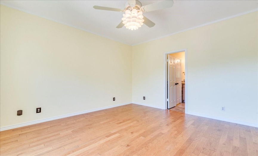 The primary bedroom offers serene ambiance, adorned with abundant natural light, wood-look luxury laminate flooring, and elegant crown molding. 