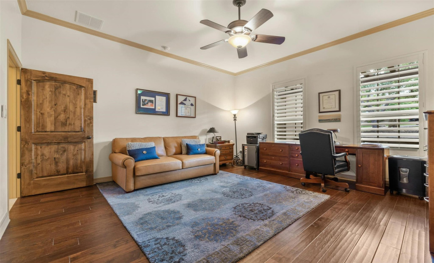 This bedroom with hardwood flooring, ceiling fan, and crown molding is currently being used as an office. All four bedrooms have their own bathrooms!