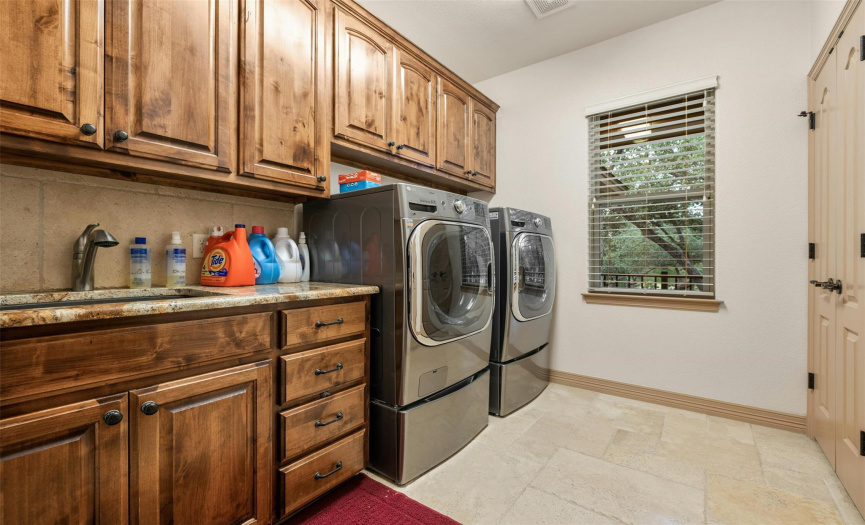 Even this separate laundry room features knotty alder hardwood, travertine tile, and a sink with a granite countertop. Lots of storage!
