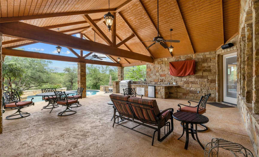 This dramatic vaulted ceiling is architecturally stunning! This covered patio is over 750 sq. ft., has ceiling fans, a gas grill connected to propane, stainless steel sink with granite counter, mini fridge, outdoor speakers, and a TV. There is access to a bathroom, the kitchen, the master suite, and the garage from the patio.